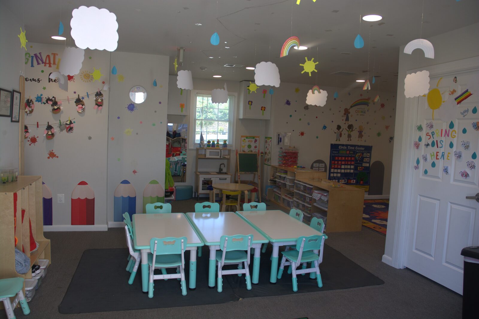 Bright classroom with child-sized tables and weather mobiles