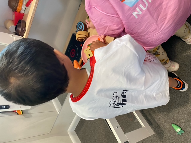 Pretend play in the classroom kitchen with a chef apron