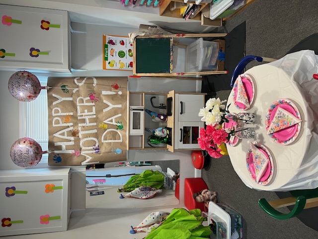 Classroom decorated with a Happy Mother's Day banner and tea party table