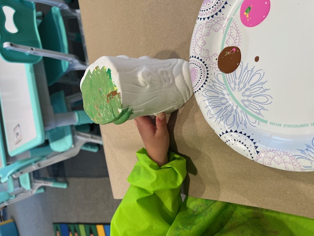 Painting a ceramic pot green during art time